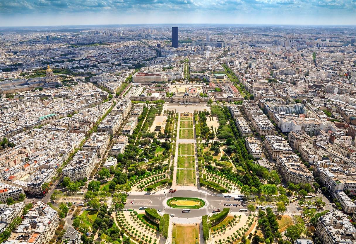 Champ de Mars gardens below, with Montparnasse Tower and Paris stretching to the horizon under blue sky