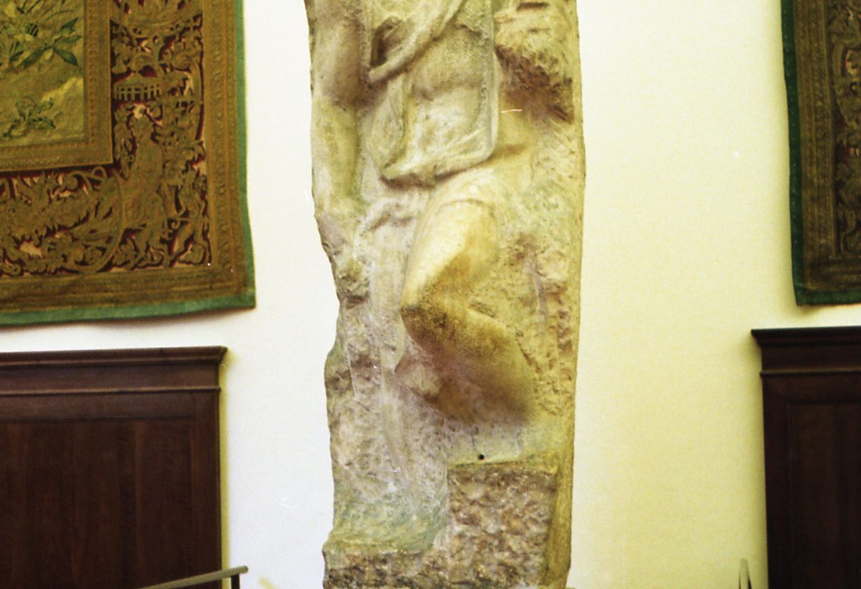Unfinished marble Prisoner by Michelangelo on a pedestal in the Accademia Gallery, flanked by tapestries