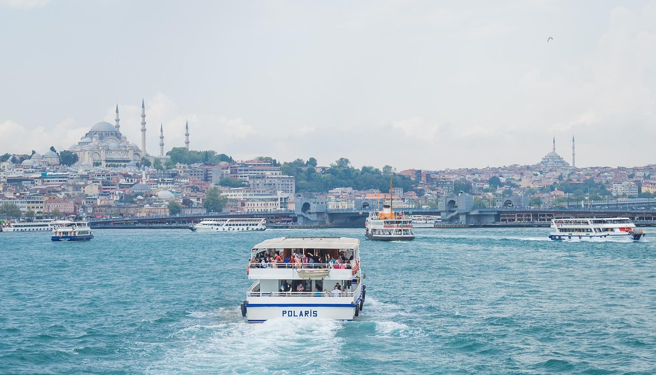 Passenger ferry crossing turquoise water toward Istanbul's old city skyline with Süleymaniye Mosque and Galata Bridge