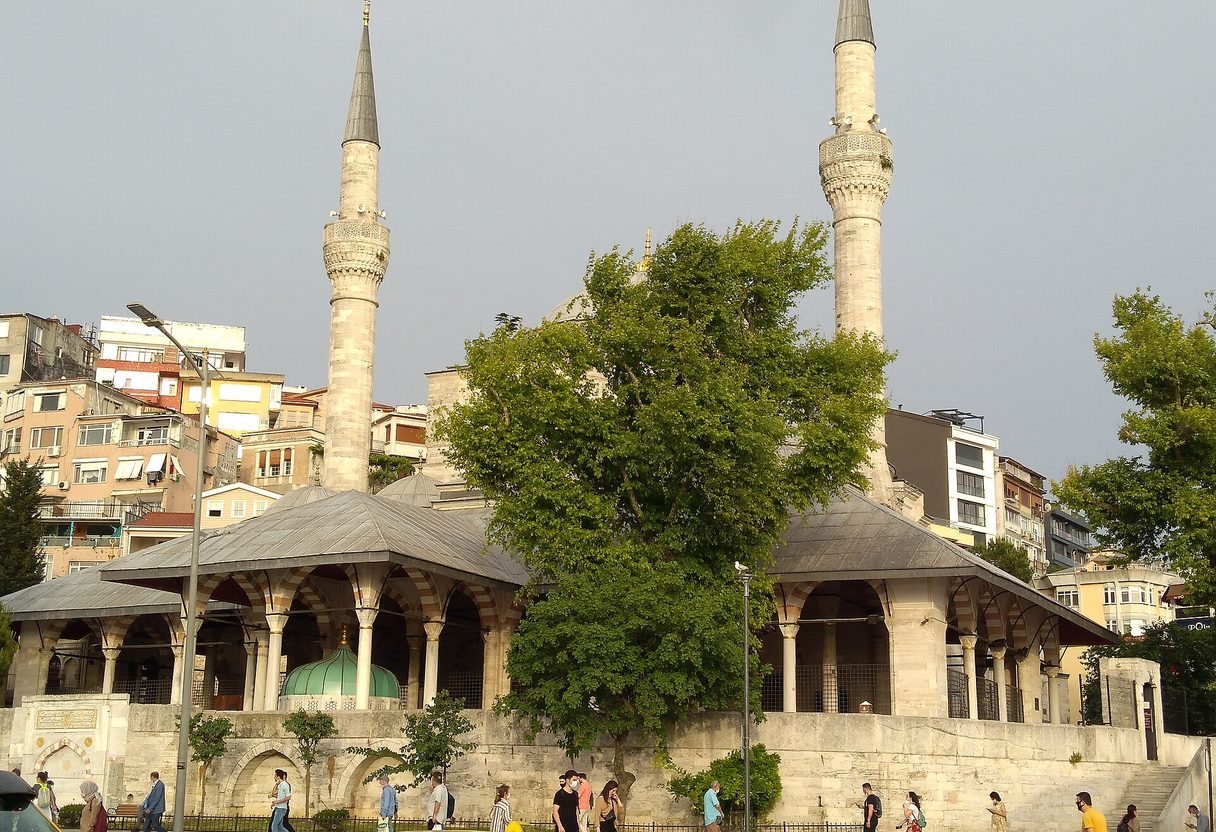 Mihrimah Sultan Mosque in Üsküdar with twin minarets, a domed portico and pedestrians on the square in front